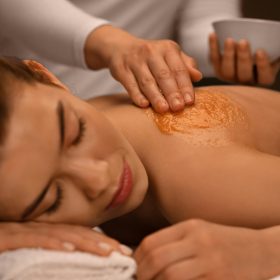 Closeup of sleeping lady getting body treatment at spa